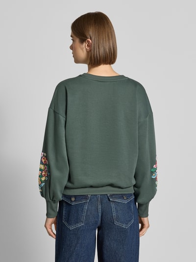 Frauenmodel trägt Relaxed Fit Sweatshirt aus reiner Baumwoll-Mix Modell 'BROOKE' von ONLY in Dunkelgrün mit bunter Stickerei auf den Ärmeln, Damen Sweatshirt von ONLY, Ganzkörperansicht Rückansicht.