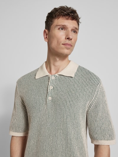 Mężczyzna nosi Slim Fit Poloshirt aus Baumwoll-Mix model 'Elwo' von Wood Wood, mieszanka bawełny, imitacja dzianiny, prążkowane wykończenia, kołnierzyk polo, krótki rękaw, długość tyłu w rozmiarze M: 72 cm, jasne paski, teksturowany materiał, nahaufnahme górnej części ciała.