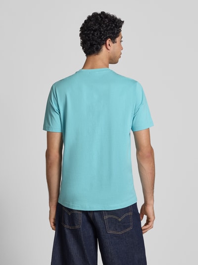 Männermodel trägt T-Shirt mit Logo-Stitchings Modell 'ICONS CONTRAST' von CHAMPION in Hellblau, Baumwoll-Mix, Modern Fit, Rückenlänge 70 cm, Ganzkörperansicht Rückansicht.