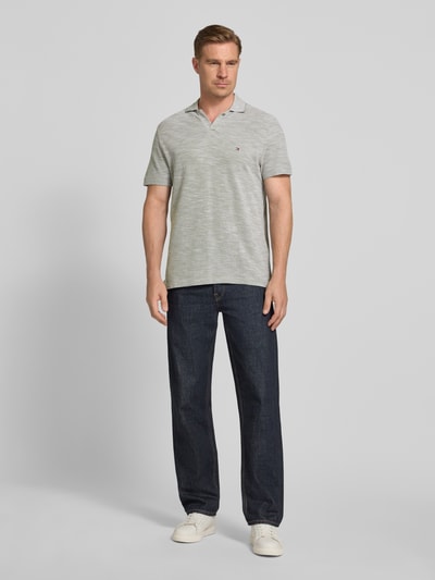 Männermodel trägt Regular Fit Poloshirt aus reiner Baumwolle von Tommy Hilfiger in Melange-Optik mit Logo-Stitching, Ganzkörperansicht von vorne.