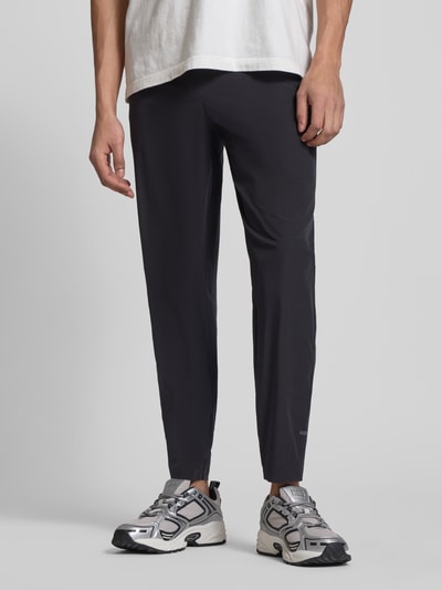 Männermodel trägt schwarze Trackpants mit elastischem Bund Modell 'EVARO' von Ellesse, Material-Mix mit Stretch, Nahaufnahme Unterkörper.