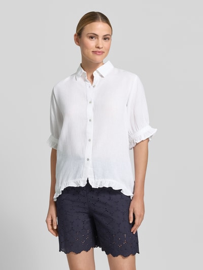 Kobiece modelka ma na sobie Bluse mit Leinen-Anteil und Rüschensaum von Christian Berg Woman, biała mieszanka wiskozy i lnu, krój regular fit, kołnierzyk koszulowy, listwa guzikowa, rękawy z falbanami, tył wydłużony z dołem z obszyciem falbaną, długość tyłu w rozmiarze 36: 68 cm, długość rękawów w rozmiarze 36: 30 cm, widok całej sylwetki z przodu.