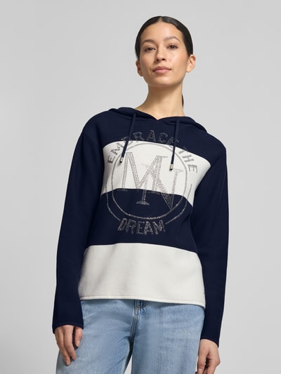 Frauenmodel trägt Strickpullover mit Kapuze und Streifenmuster von monari aus reiner Baumwolle, Regular-Fit, Logo, Ganzkörperansicht von vorne.