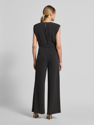 Frauenmodel trägt Jumpsuit mit V-Ausschnitt und Bindegürtel von Comma, schwarz, Material-Mix mit Stretch-Anteil, Regular-Fit, Ganzkörperansicht Rückansicht.