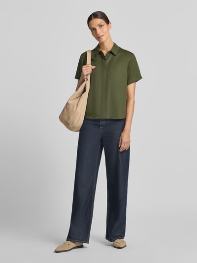 Frauenmodel trägt Relaxed Fit Bluse aus reinem Lyocell Modell 'Mina' von Samsøe Samsøe in Olivgrün, kombiniert mit Jeans, Ganzkörperansicht von vorne. Hemdblusenkragen und kurzärmeliges Design, Rückenlänge in Größe S 60 cm, Ärmellänge 22 cm.