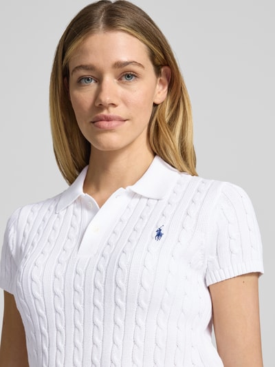 Frauenmodel trägt Regular Fit Strick-Poloshirt aus reiner Baumwolle von Polo Ralph Lauren in Weiß mit Zopfmuster, Nahaufnahme Oberkörper.