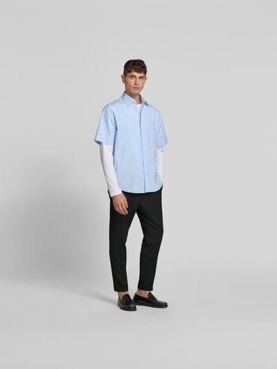 Männermodel trägt Slim Fit Anzughose mit Woll-Anteil von Filippa K, Elastischer-Material-Mix, Eingrifftaschen, Bundfalten, Ganzkörperansicht von vorne.