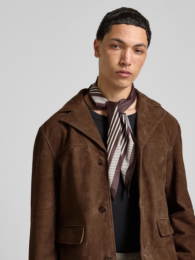 Männermodel trägt Lederjacke aus echtem Ziegenleder von Officine Générale in Braun mit Reverskragen und Pattentaschen, Nahaufnahme Oberkörper.