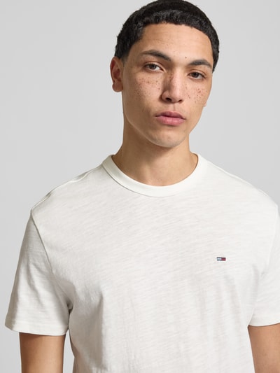 Männermodel trägt Regular Fit T-Shirt aus reiner Baumwolle von Tommy Jeans in Unifarbe mit Logo-Detail, Nahaufnahme Oberkörper.