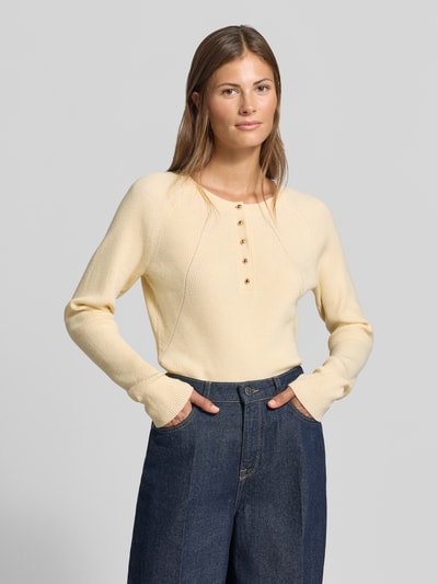 Frauenmodel trägt Slim Fit Longsleeve aus Strick-Optik od MYON, okrągły dekolt, listwa guzikowa, długość tyłu 60 cm, długość rękawów 66 cm, imitacja dzianiny, krój slim fit, kremowy kolor, gładka tekstura, Ganzkörperansicht von vorne.