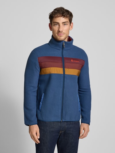 Männermodel trägt Jacke mit Stehkragen Modell 'Teca' von Cotopaxi in Blau mit Label-Print, Regular-Fit, Eingrifftaschen, Ganzkörperansicht von vorne. Rückenlänge 68 cm, Schulterbreite 43 cm, Brustweite 42 cm, Ärmellänge 63 cm.