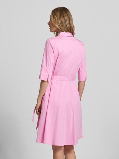 Vrouwenmodel draagt Knielanges Hemdblusenkleid met Bindegürtel van Christian Berg Woman Selection, katoenmix met stretch, a-lijn, knielengte, verborgen knoopsluiting, strikceintuur, ruglengte maat 36: 99 cm, borstwijdte maat 36: 48 cm, mouwlengte maat 36: 37 cm, effen roze, gladde stofstructuur. Ganzlichaansicht achteraan.