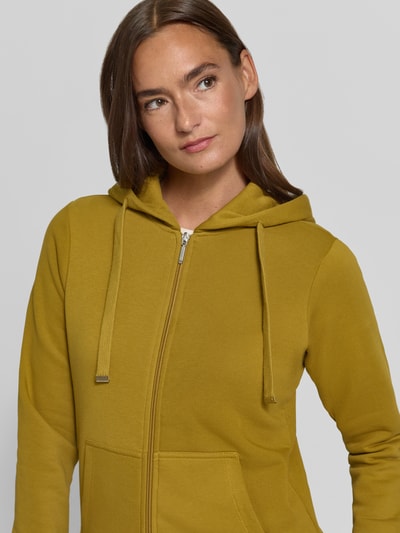 Kobiece model prezentuje Regular Fit Sweatjacke aus Baumwoll-Mix od Christian Berg Woman, kolor musztardowy, kieszeń kangurka, kaptur z tunel, mieszanka bawełny, krój regular fit, taliowany krój, elastyczne wykończenia, zbliżenie na górną część ciała.