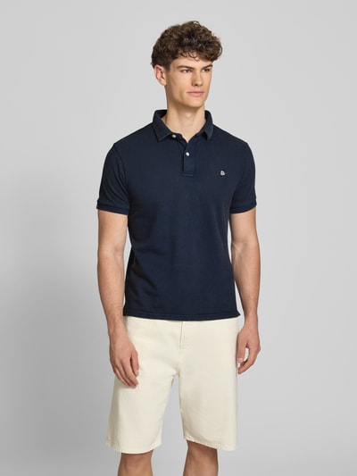 Męski model nosi Regular Fit Poloshirt mit Logo-Stitching od Superdry, czysta bawełna, krój regular fit, granatowy, krótki rękaw, polokołnierzyk, widok całej sylwetki z przodu, długość pleców w rozmiarze M: 67 cm