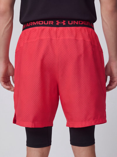 Männermodel trägt Relaxed Fit Sportshorts im Double-Layer-Look von Under Armour in Rot mit schwarzem Bund, Ganzkörperansicht Rückansicht, Herren Sportshorts von Under Armour.