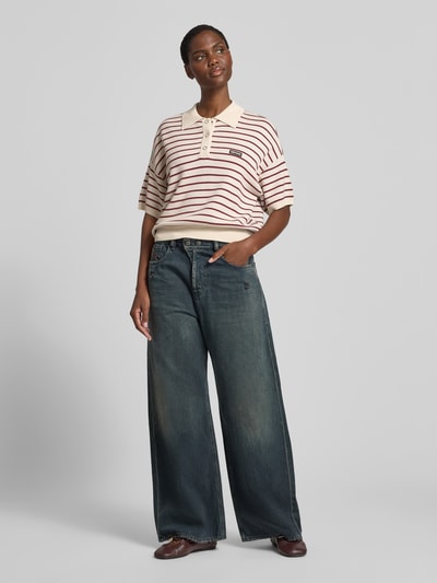 Frauenmodel trägt Relaxed Poloshirt mit Woll-Anteil von ROTATE im Modal-Mix, Streifen, Polokragen, Strick-Optik, Kurzärmelig, Relaxed-Fit, Rückenlänge 52 cm, Ganzkörperansicht von vorne.