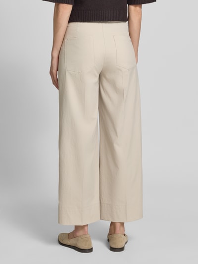 Frauenmodel trägt Stoffhose mit Eingrifftaschen Modell 'CARA' von Cambio in Beige mit Wide-Fit, Haken- und Reißverschluss, Ganzkörperansicht Rückansicht.