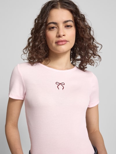 Frauenmodel trägt Slim Fit Damen T-Shirt mit Herz-Stickerei Modell 'ELVA JUNE' von Only, Optik: Unifarben, Nahaufnahme Oberkörper.