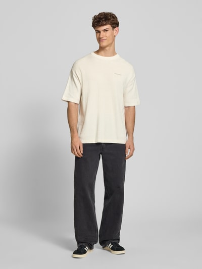 Męski model nosi Strickshirt mit Strukturmuster und Label-Stitching von Pegador z bawełny, krój relaxed fit, okrągły dekolt, długość tyłu 71 cm, fakturowany wzór, wyhaftowane logo, widok całej sylwetki z przodu.