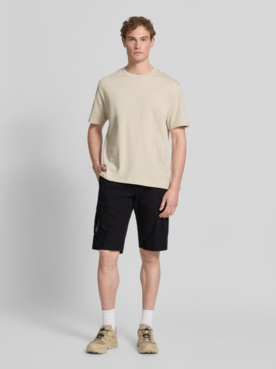 Männermodel trägt Relaxed Fit Cargoshorts aus reiner Baumwolle von s.Oliver BLACK LABEL, schwarze Optik: Unifarben, Label-Patch, seitliche Eingrifftaschen, Cargotaschen, Knopf und verdeckter Reißverschluss, Ganzkörperansicht von vorne