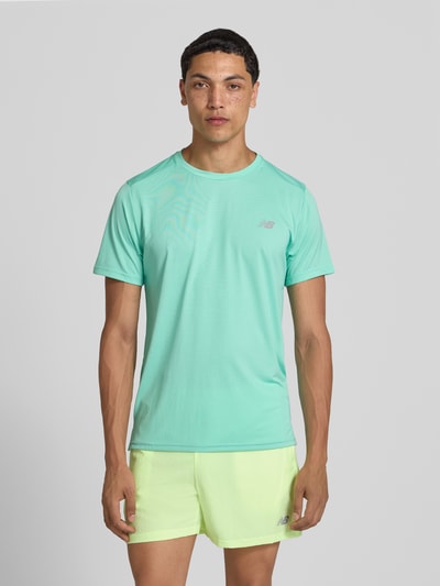 Männermodel trägt Funktionsshirt mit Rundhalsausschnitt und Logo von New Balance in Türkis, Regular-Fit, glatte Struktur, Ganzkörperansicht von vorne, Rückenlänge bei Größe M: 69 cm