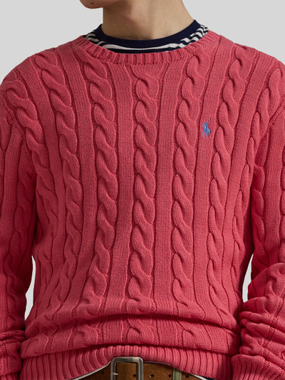 Męski model nosi Regular Fit Strickpullover aus reiner Baumwolle od Polo Ralph Lauren, różowy sweter w splot warkoczowy, logo, bawełna, okrągły dekolt, długi rękaw, widok na górną część ciała z przodu.