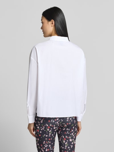 Frauenmodel trägt Relaxed Fit Hemdbluse aus reiner Baumwolle von Marc Cain in Weiß, glatte Textur, Brusttasche, Ganzkörperansicht Rückansicht. Reine Baumwolle, Hemdblusenkragen, Langarm, Logo-Print, Stehkragen mit Tunnelzug, Rückenlänge 59 cm, Ärmellänge 52 cm.