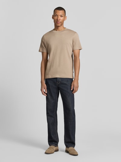 Männermodel trägt Herren T-Shirt mit Strukturmuster Modell 'Raulos' von JOOP! Collection, Reine Baumwolle, Modern Fit, Rundhalsausschnitt, Label-Detail, Rückenlänge 68 cm bei Größe M, beige, Ganzkörperansicht von vorne.