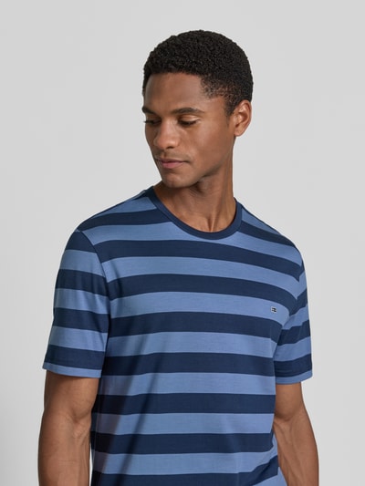 Męskimodel nosi Regular Fit T-Shirt mit Logo-Stitching von Christian Berg Men aus bawełny, okrągły dekolt, długość tyłu 70 cm, rozmiar M, niebieskie pasy, tekstura gładka, ujęcie: z przodu, półzbliżenie.