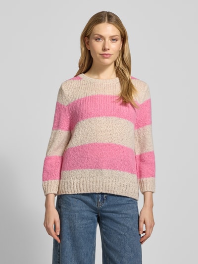 Modelka kobieca nosi Strickpullover mit gerippten Abschlüssen od Oui, luźny krój, okrągły dekolt, różowo-beżowe pasy, widok całej sylwetki z przodu.