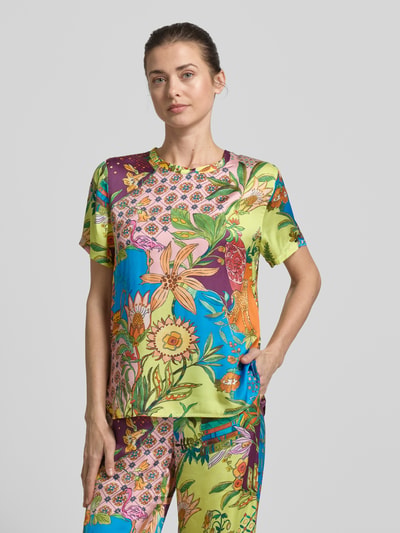 Frauenmodel trägt Relaxed Fit T-Shirt aus reiner Viskose von Liu Jo White mit Floraler-Print, bunten Farben, Rundhalsausschnitt, Ganzkörperansicht von vorne.
