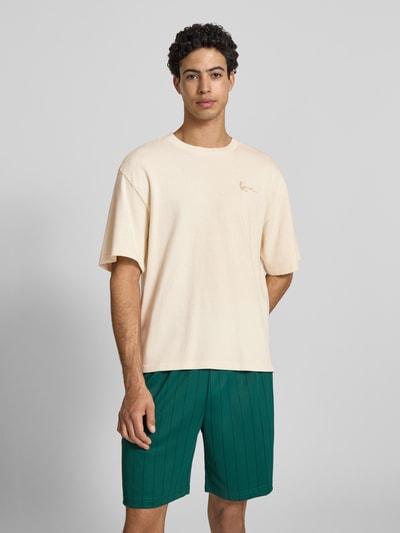 Männermodel trägt Oversized T-Shirt mit Logo-Stitching von KARL KANI aus Reine Baumwolle, Oversized-Fit, Rundhalsausschnitt, Ganzkörperansicht von vorne. Herren T-Shirt, Rückenlänge bei Größe M 65 cm, beige, glatte Textur, schlichte Optik.