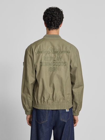 Männermodel trägt Bomberjacke mit Reißverschlusstasche am Ärmel von Replay aus Baumwoll-Mix, Gerader-Schnitt, Rückenlänge 68 cm, Ganzkörperansicht Rückansicht.