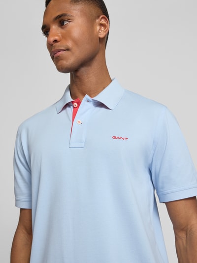 Männermodel trägt Regular Fit Poloshirt mit Logo-Stitching von Gant in Hellblau, Baumwoll-Mix, Polokragen, Kurzärmelig, Nahaufnahme Oberkörper.