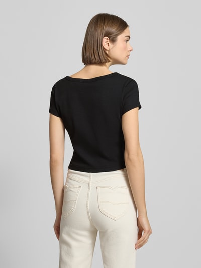 Kobiece modelka ma na sobie Cropped T-Shirt mit Label-Detail od Calvin Klein Jeans z mieszanki bawełny i elastanu, czarny kolor, krój krótki, okrągły dekolt, długość tyłu 43 cm dla rozmiaru S, widok całej sylwetki z tyłu.