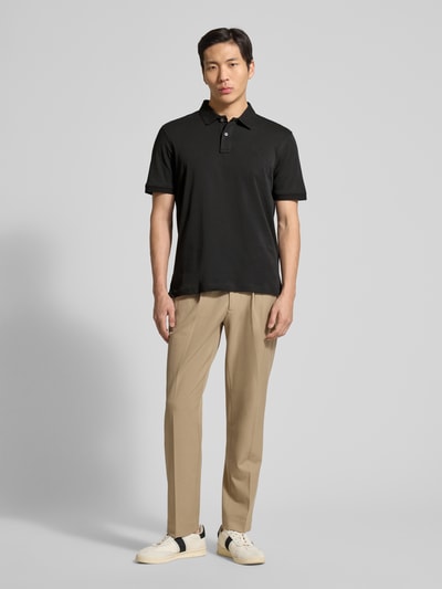 Männermodel trägt schwarzes Regular Fit Poloshirt mit Logo-Stitching von Fynch-Hatton, reine Baumwolle, Ganzkörperansicht von vorne.