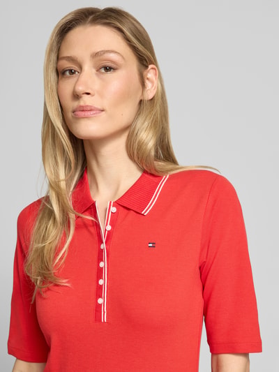 Frauenmodel trägt Slim Fit Poloshirt aus Lyocell-Mix von Tommy Hilfiger, Optik: Unifarben, Logo-Stitching, Kontraststreifen, Knopfleiste, 1/2-Arm, Materialverarbeitung: Piqué, Nahaufnahme Oberkörper.