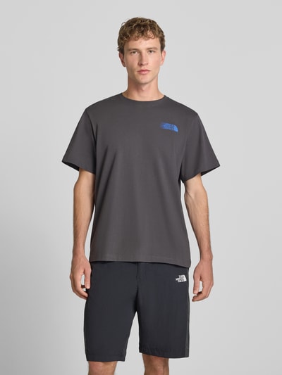 Männermodel trägt Relaxed Fit T-Shirt mit Logo-Print von The North Face in Dunkelgrau, reine Baumwolle, Rundhalsausschnitt, Ganzkörperansicht von vorne.