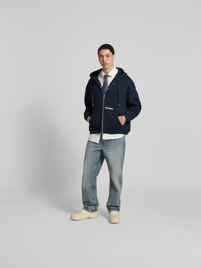 Männermodel trägt Oversized Sweatjacke aus Baumwoll-Mix von Dsquared2, dunkelblau, Reißverschluss, Kängurutasche, Ganzkörperansicht von vorne.