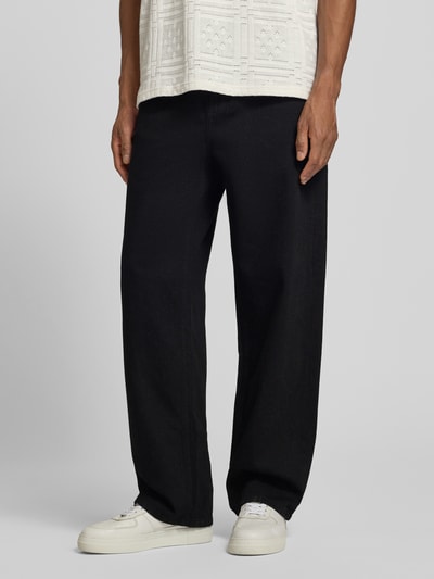Mężczyzna nosi czarne spodnie Loose Fit Jeans im 5-Pocket-Design Modell 'Roi' od Les Deux z bawełny, szeroki krój, zbliżenie na nogi.