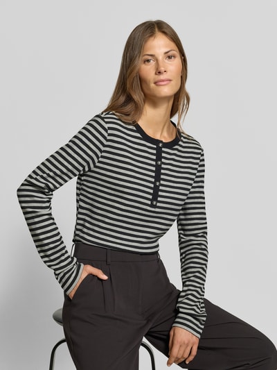 Frauenmodel trägt Longsleeve mit Henley-Kragen von MYON, schwarz-grau gestreift, taillierter Schnitt, Ripp-Struktur, Nahaufnahme Oberkörper.