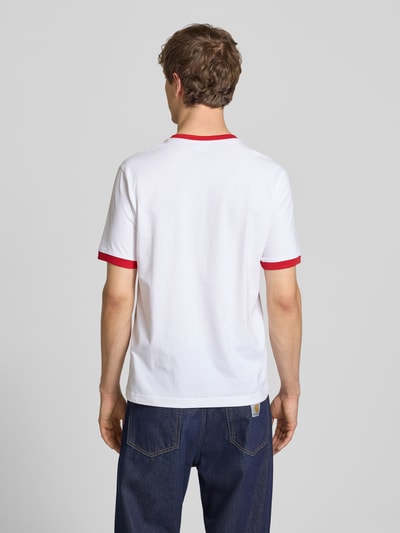 Männermodel trägt weißes T-Shirt mit Rundhalsausschnitt und Label-Stitchings von CHAMPION, rote Akzente, Regular Fit, Ganzkörperansicht Rückansicht.