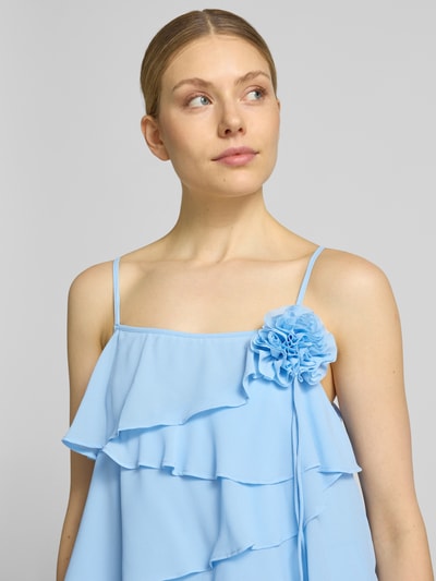 Frauenmodel trägt fließendes Cocktailkleid mit Volants Modell 'ALADYN' von Vero Moda in Optik: Unifarben, Zierblüte, Trägerform: Spaghettiträger, Nahaufnahme Oberkörper.