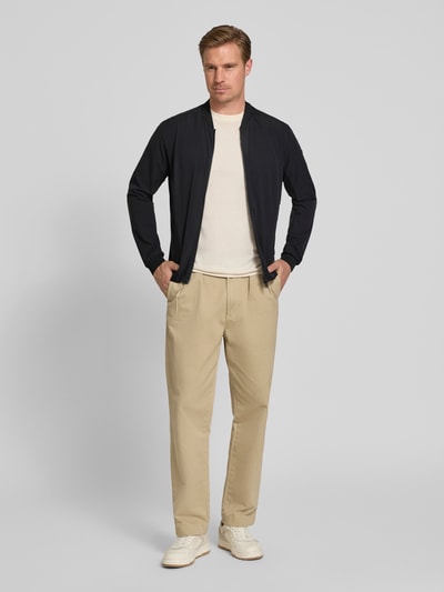 Männermodel trägt Regular Fit Jacke mit Stehkragen Modell 'Campo' von SCANDINAVIAN EDITION, Zweiwege-Reißverschluss, Eingrifftaschen, elastische Abschlüsse, gerade beige Hose, helle Sneakers, Ganzkörperansicht von vorne. Rückenlänge bei Größe M: 67 cm, Schulterbreite: 44 cm, Brustweite: 51 cm, Ärmellänge: 64 cm.