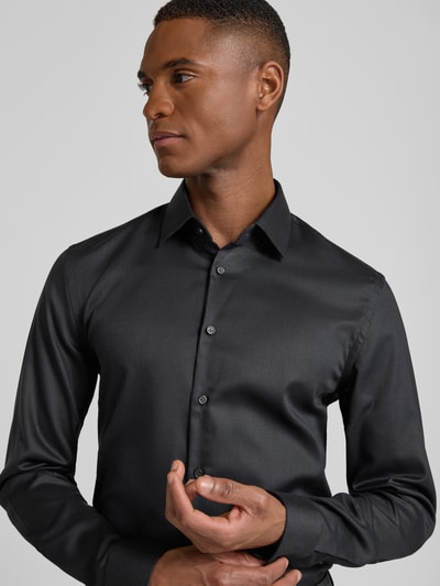 Männermodel trägt schwarzes Slim Fit Businesshemd in Premiumqualität von Jake*s, feines Allover-Muster, Kentkragen, Nahaufnahme Oberkörper.