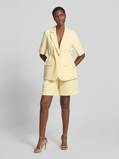 Modelka prezentuje żakiet Relaxed Fit Blazer mit Viskose-Anteil Model 'Likka' od YAS, elastyczna mieszanka materiałów z dodatkiem wiskozy, krój relaxed fit, kołnierz z połami, rękaw o dł. 1/2, zapięcie na guzik, kieszenie z patką, długość tyłu w rozmiarze 36: 70 cm, jasny żółty odcień, matowa faktura, całopostaciowy widok z przodu