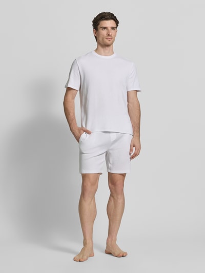 Männermodel trägt Regular Fit Pyjama-Oberteil aus Baumwoll-Mix Modell 'WAFFLE' von BOSS, Optik: Unifarben, Label-Stitching-Applikation, Kragenform: Rundhals, Ärmelform: Kurzarm, Materialverarbeitung: Piqué, Ganzkörperansicht von vorne.