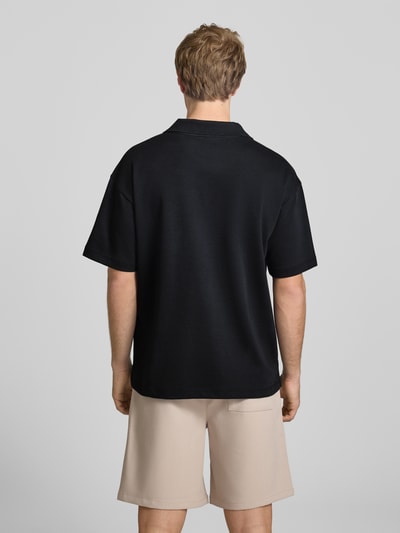 Männermodel trägt Boxy Fit Poloshirt aus Baumwoll-Mix Modell 'CASPIAN AIRLEX' von Only & Sons in Schwarz, unifarben, kurzarm, Ganzkörperansicht Rückansicht.