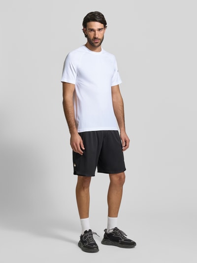 Männermodel trägt weißes Regular Fit T-Shirt mit Logo-Print Modell 'The Training Day' von Fabletics, Rundhalsausschnitt, Ganzkörperansicht von vorne.