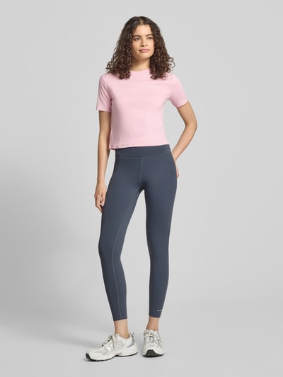 Modelka prezentuje damski t-shirt z okrągłym dekoltem od Topshop z bawełny, krój taliowany, długość tyłu w rozmiarze S: 47 cm, cała sylwetka z przodu.